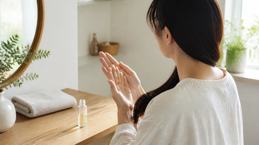 洗面台で少量のヘアオイルを手のひらに広げる女性