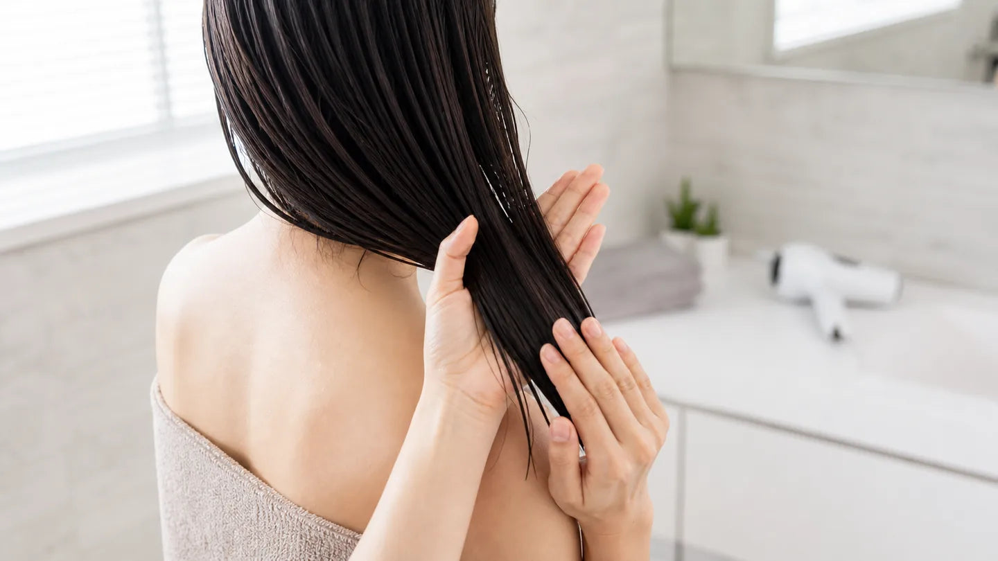 タオルドライ後の毛先に少量のヘアオイルをなじませる女性